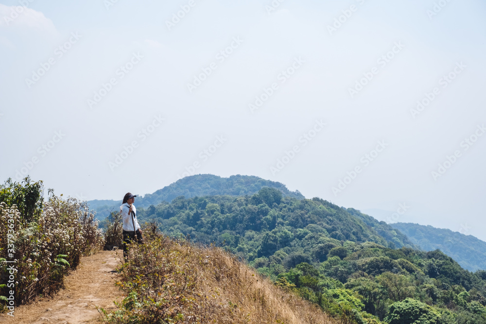 Plakat A woman hiking and standing on the top of mountains with blue sky background