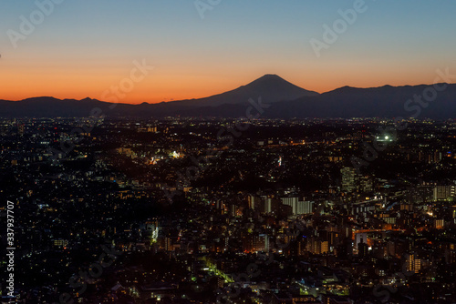 横浜の街並みの向こうに見える富士山の夕焼けのシルエット