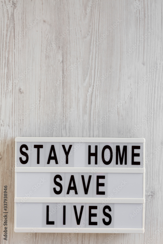 'Stay Home Save Lives' words on a lightbox on a white wooden background, top view. Overhead, from above, flat lay. Copy space. 'Stay Home Save Lives' words on a lightbox on a white wooden background, top view. Overhead, from above, flat lay. Copy space.