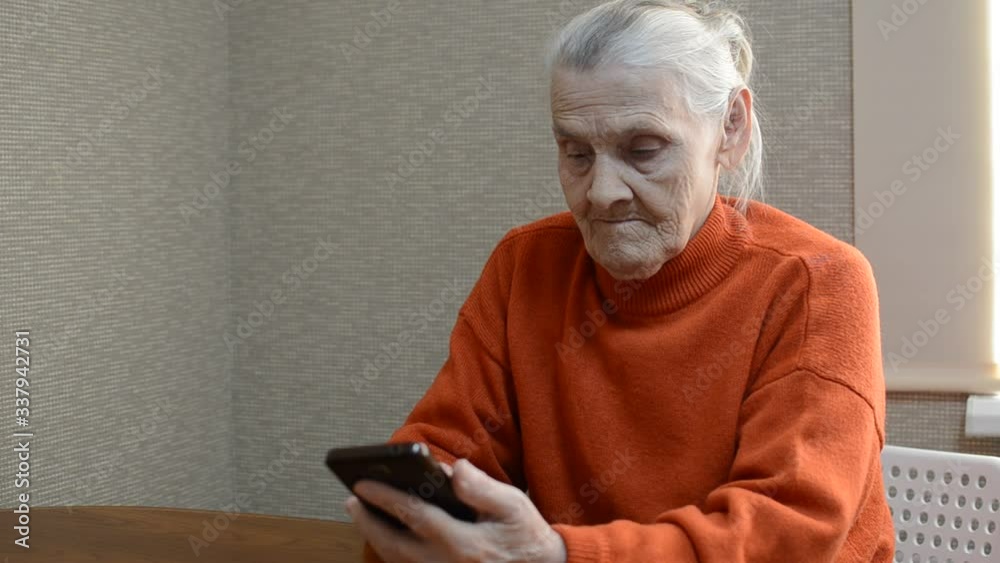 Elderly woman writes a message in a smartphone Elderly woman writes a message in a smartphone