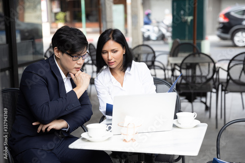 Asian business men and business woman working with laptop computer at a co-working space, Coffee shop. Communication and Brainstorm