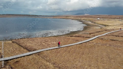 Aerial drone shot of walking couple on claggan mountain coastal trail slow motion  Irish destination. County Mayo Ireland. photo