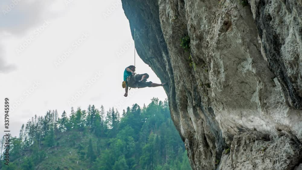 Adult Male Climbing Cliff Wall And Falls And Hangs In Air At Burjakove Peci. Slow Motion