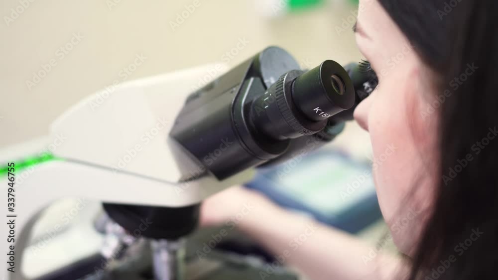 A woman looks through a microscope. A researcher examines the bacteria in a microscope. Virus under the microscope. Scientific laboratory. A woman looks through a microscope. A researcher examines the bacteria in a microscope. Virus under the microscope. Scientific laboratory.