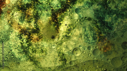 Mixing water and oil, beautiful colors. Close-up. Abstract background of filaments of different colors. Water and oil bubbles. Abstract green light illumination