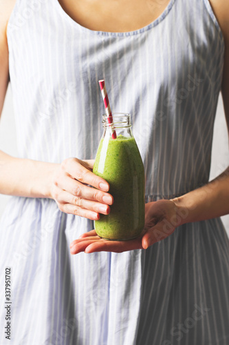 Female hands holding a bottle with green smoothie
