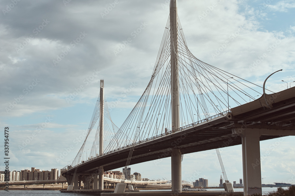 Fototapeta premium modern cable stayed bridge over the river against cloudy sky. Engineering construction closeup