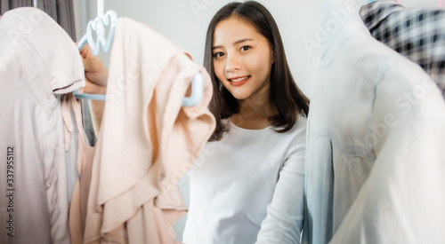 Portrait of young asian woman .Beautiful young woman standing and trying on dress.Smiling girl holds dress while choosing clothes.