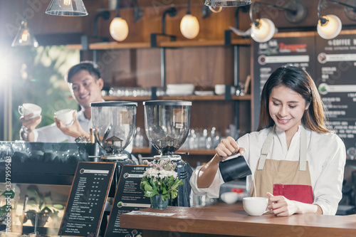 Asian Barista preparing cup of coffee, espresso with latte or cappuccino for customer order in coffee shop