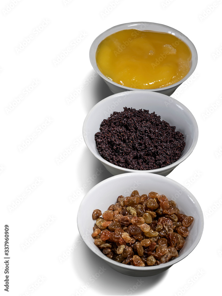 Poppy seeds, honey and raisins in white plates isolated on white background. The components of the filling for rolls and buns. Close-up, selective focus, top view. Poppy seeds, honey and raisins in white plates isolated on white background. The components of the filling for rolls and buns. Close-up, selective focus, top view.