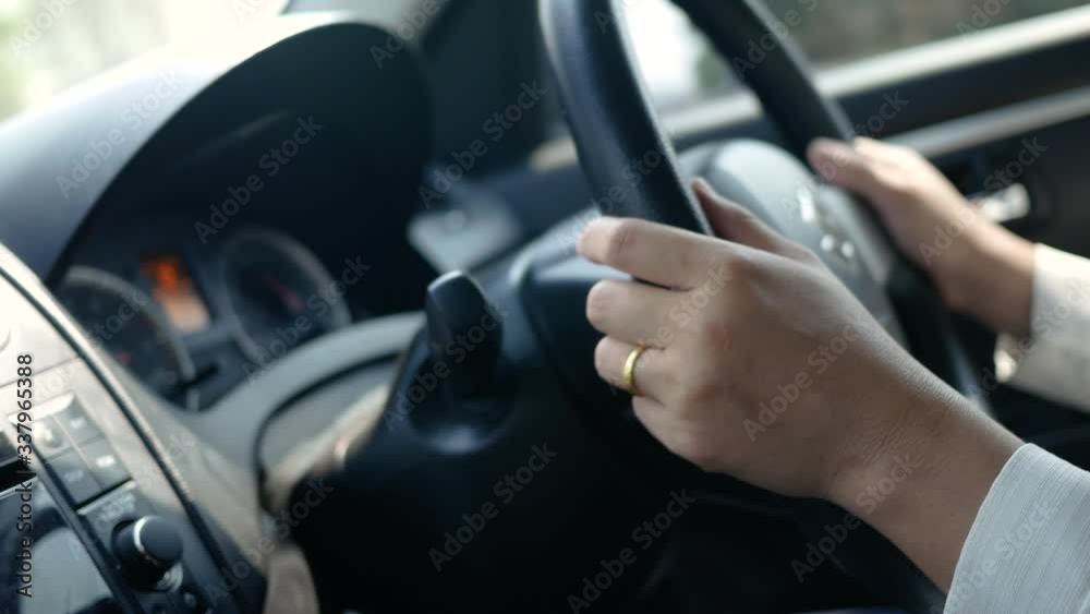 Young woman driving a car, hand put on the black steering wheel and looking forward drive with caution. Young woman driving a car, hand put on the black steering wheel and looking forward drive with caution.
