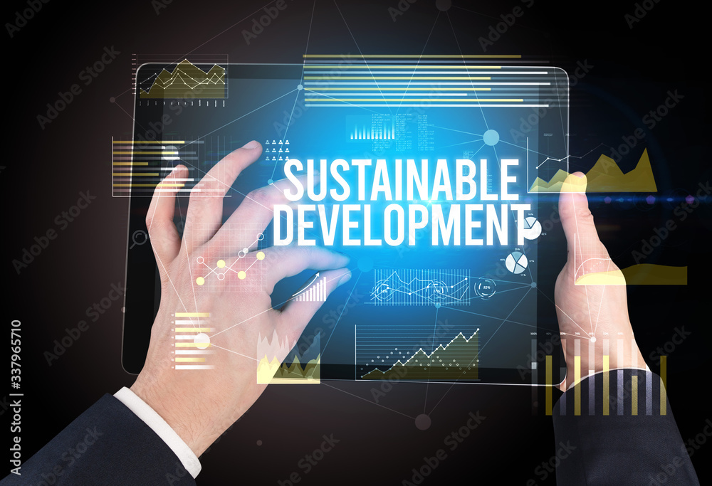 Close-up of hands holding tablet with SUSTAINABLE DEVELOPMENT inscription, modern business concept Close-up of hands holding tablet with SUSTAINABLE DEVELOPMENT inscription, modern business concept