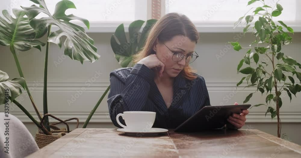 Beautiful mature woman in pajamas reading news in digital tablet Beautiful mature woman in pajamas reading news in digital tablet