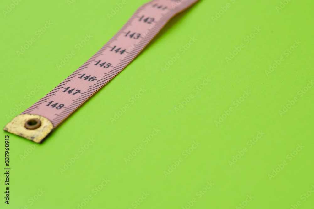 Close up of measuring tape against green background Close up of measuring tape against green background