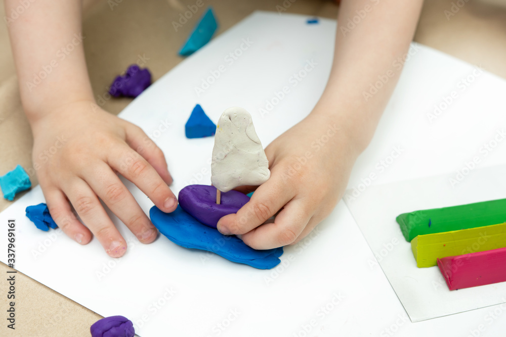 plasticine boat in children's hands on a white background. close-up. plasticine boat in children's hands on a white background. close-up.