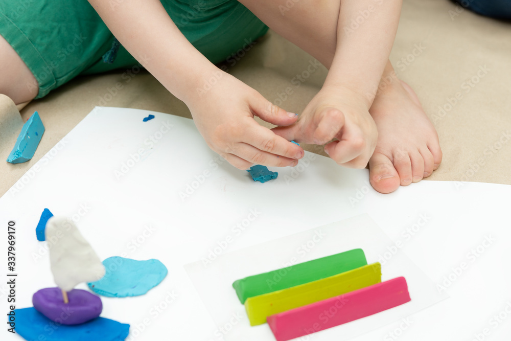 plasticine sailboat on the background of children's hands and colorful pieces. Children's crafts for kindergarten and school. plasticine sailboat on the background of children's hands and colorful pieces. Children's crafts for kindergarten and school.