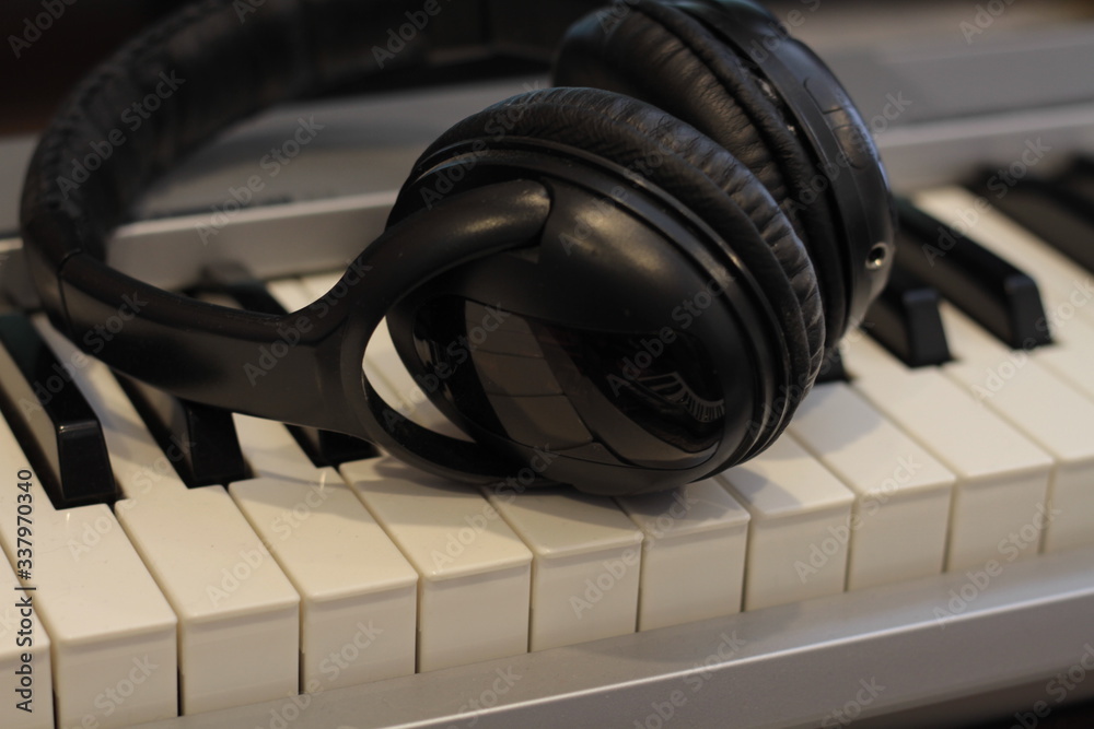 Black headphones on the keyboard, red headphones on the laptop, electronic piano keys Black headphones on the keyboard, red headphones on the laptop, electronic piano keys