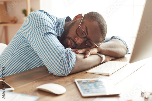 Taking a break. Tired afro american man in glasses sleeping at his working place at home. Afro american businessman feeling exhausted and sleeping at work