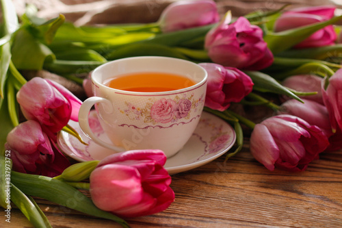  tulips and a cup of tea on wooden background