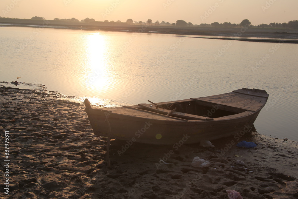 Old wooden boat at river shore with sunset. Old boat vintage look with sunset horizon in evening