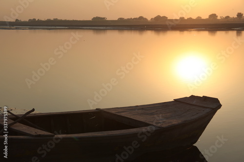 wooden boat at river shore with sunset. Old boat vintage look with sunset horizon in evening