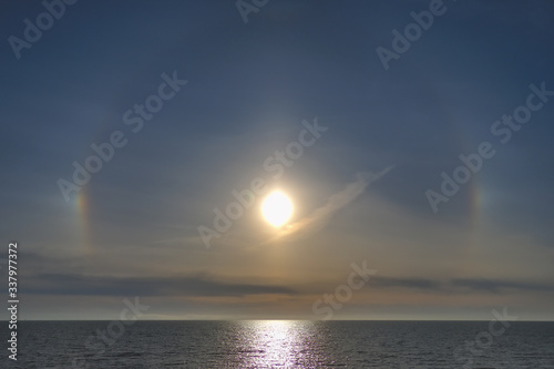 Rainbow glow around the sun in a haze above the sea. Halo - a sign of worsening weather © Igor