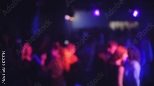 crowd of people dancing on the dance floor of a night club under the light of colored spotlights and lasers