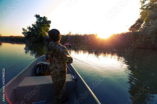 Tableau sur toile Anglers fishing from the boat on the calm river in Astrakhan Region in Russia