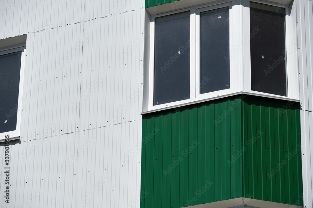 facade of a new multistory building with white and green metal siding, many Windows facade of a new multistory building with white and green metal siding, many Windows