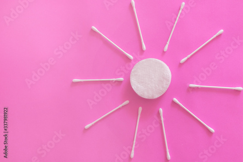 cotton buds and makeup cleaning discs on a pink background with copy space