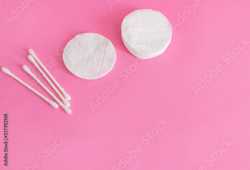 cotton buds and makeup cleaning discs on a pink background with copy space