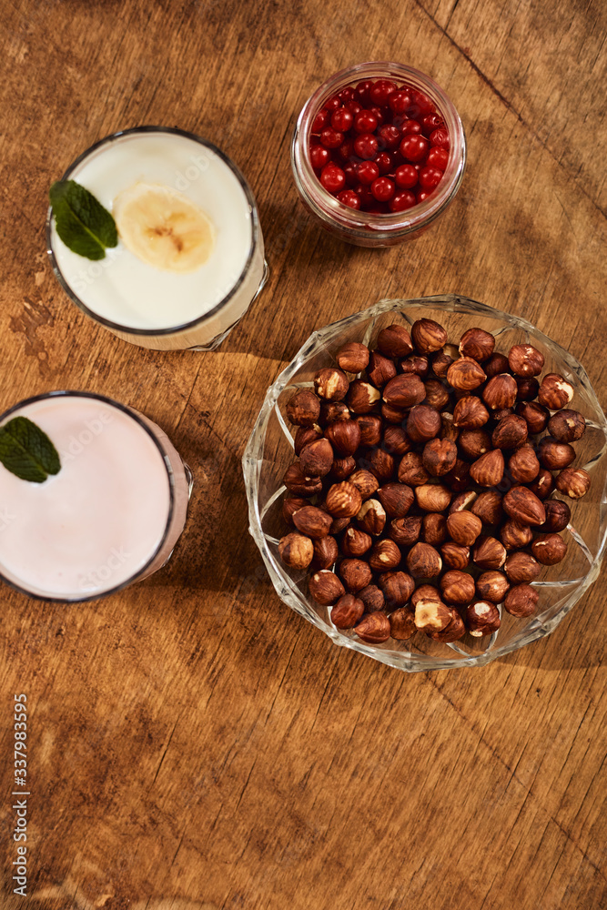 Yogurt with nuts on a wooden background. View from above. Summer food. Yogurt with nuts on a wooden background. View from above. Summer food.