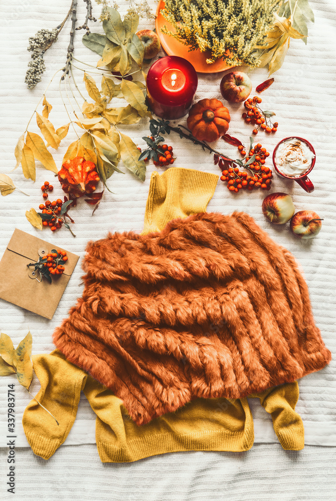 Φωτογραφία Female autumn outfit with sweater and  faux fur poncho on white blanket with fall leaves, pumpkins ,candle and mug with cappuccino , top view