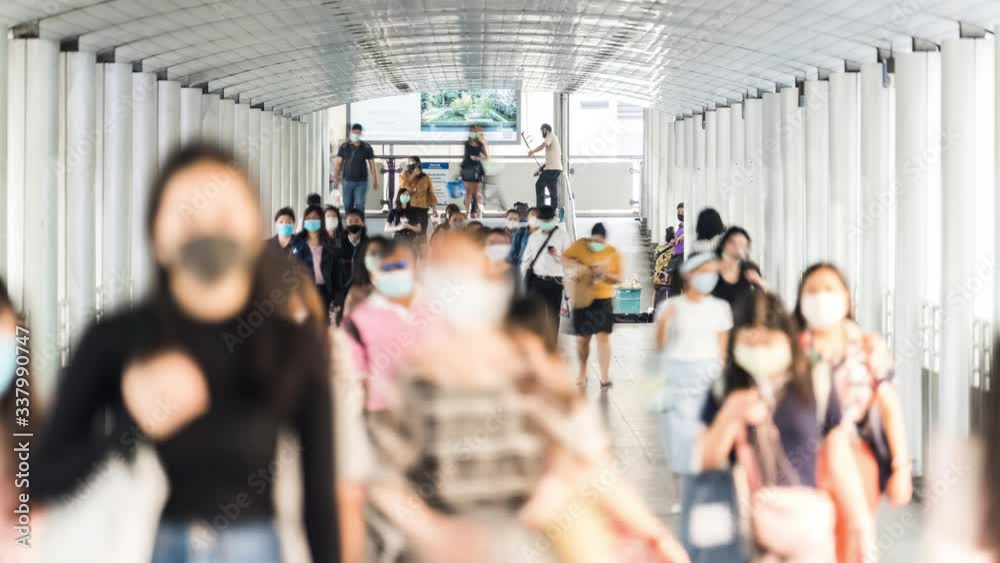 4K time-lapse of crowded Asian people wear face mask, walk in pedestrian walkway. Coronavirus disease Covid-19 pandemic outbreak effect, social distancing, city life or PM 2.5 air pollution concept