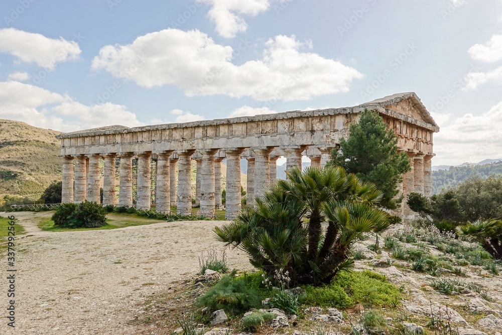Ancient Doric temple of Segesta hidden behind the trees in nice sunny spring day in Sicily