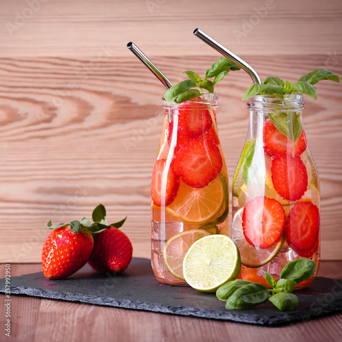 Refreshing drink or water with strawberry, citrus fruits lemon, lime and basil in mason jar with reusable metal straws. Healthy lemonade drink in glass jar, zero waste concept, sustainable lifestyle