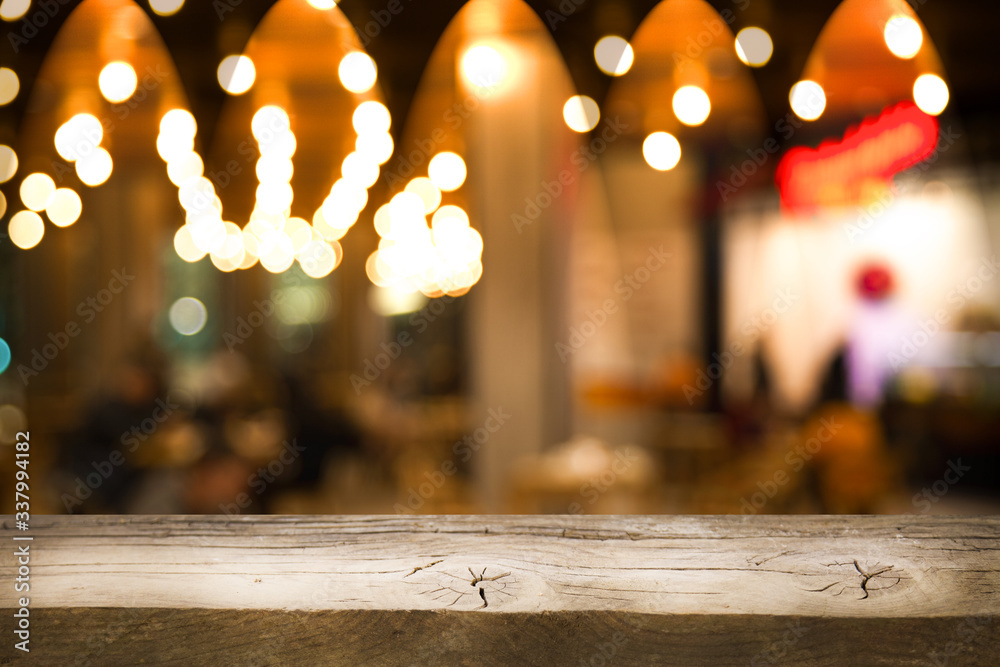 Empty wooden table from above on blur light golden bokeh cafe restaurant, bar on a dark background. with a ray of light on the table. Empty wooden table from above on blur light golden bokeh cafe restaurant, bar on a dark background. with a ray of light on the table.