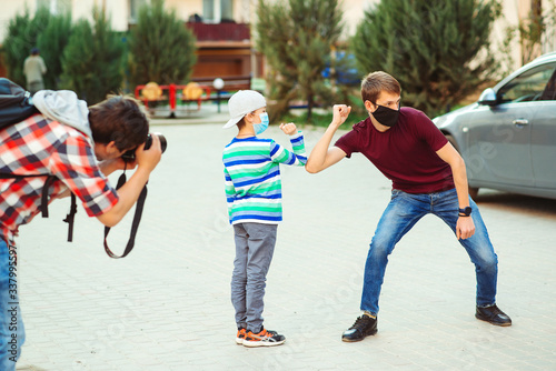 A photographer shoot people with face mask outdoors. New greeting style with elbows.