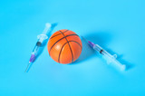 Basketball ball near syringe on blue background. Concept of doping in professional sport. Rehabilitation, treatment after competition. Illegal medicaments using on tournament