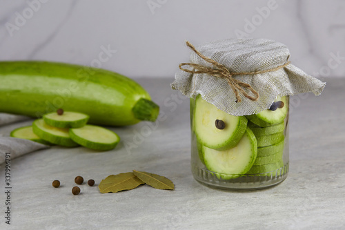 Fermented zucchini in a jar on a light background  photo