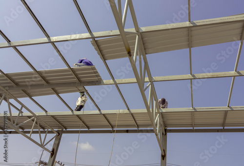 Φωτογραφία Three men are installing the roofing sheet on Light steel Truss and Frame construction