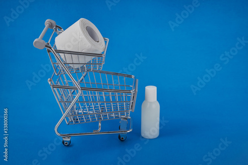 hygiene against viruses and bacteria concept, a bottle of hand sanitizer, toilet paper and soap inside a shopping basket symbol of highly sought-after products in times of self-isolation and quarantin photo