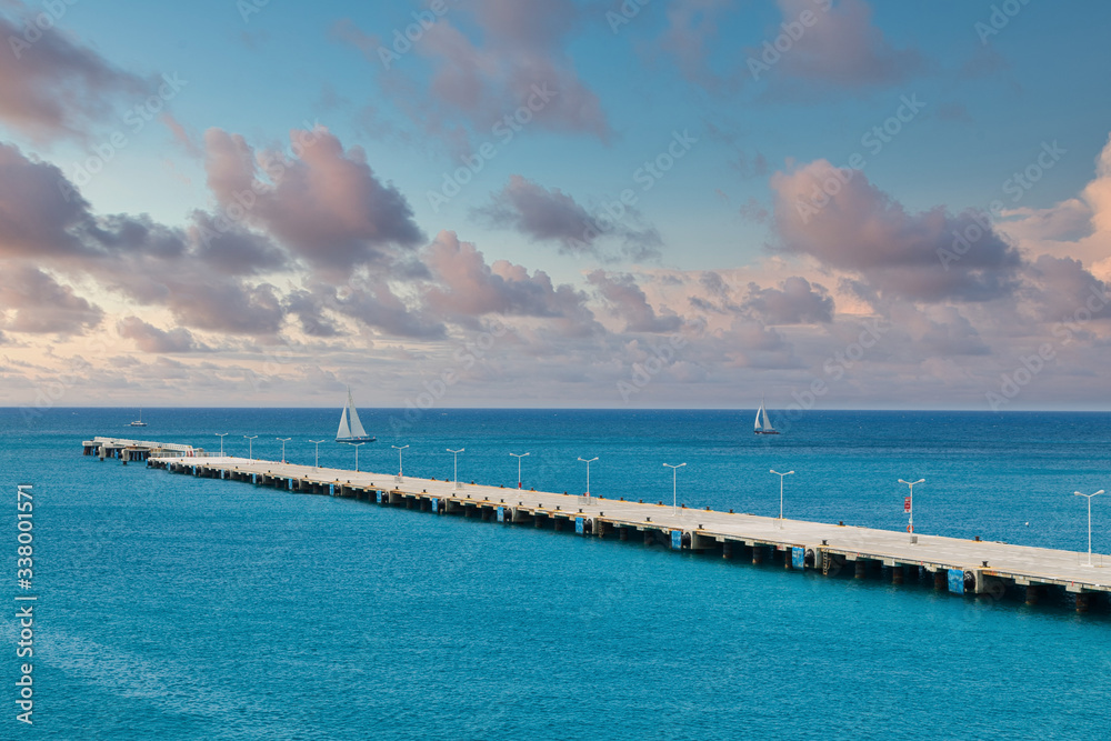 Concrete pier extending far into clear aqua water of the Caribbean