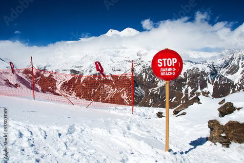Fototapeta Avalanche warning sign and net fence in Caucasus mountains