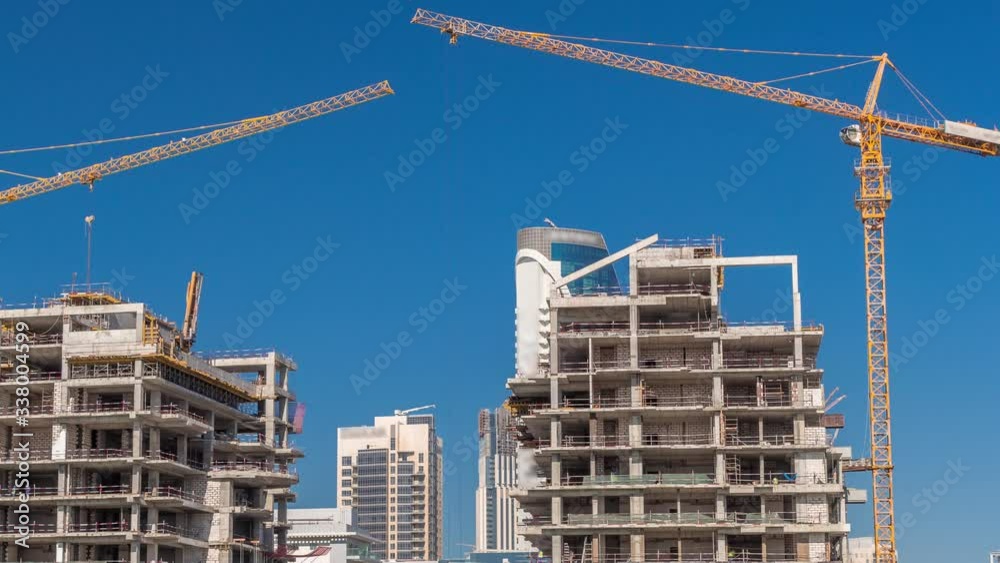 Aerial view of a skyscrapers under construction with huge cranes timelapse in Dubai. Business bay district with blue sky on a background. United Arab Emirates Aerial view of a skyscrapers under construction with huge cranes timelapse in Dubai. Business bay district with blue sky on a background. United Arab Emirates