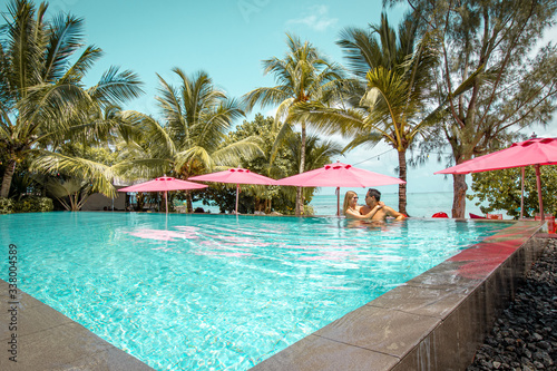 Paar entspannt am Pool umgeben von Palmen mit Meerblick auf Mauritius