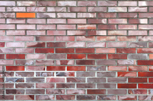 one orange-colored brick stands out from the other bricks that make up the wall fragment