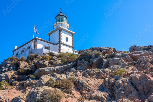 Greek Lighthouse and Flag on a Sunny Cliff