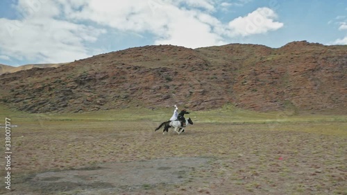 Nomadic Mongolian horse riders galloping across Altai Mountains Steppe photo