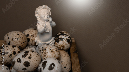 Еaster background. Delicate white angel on a brown background with small eggs.